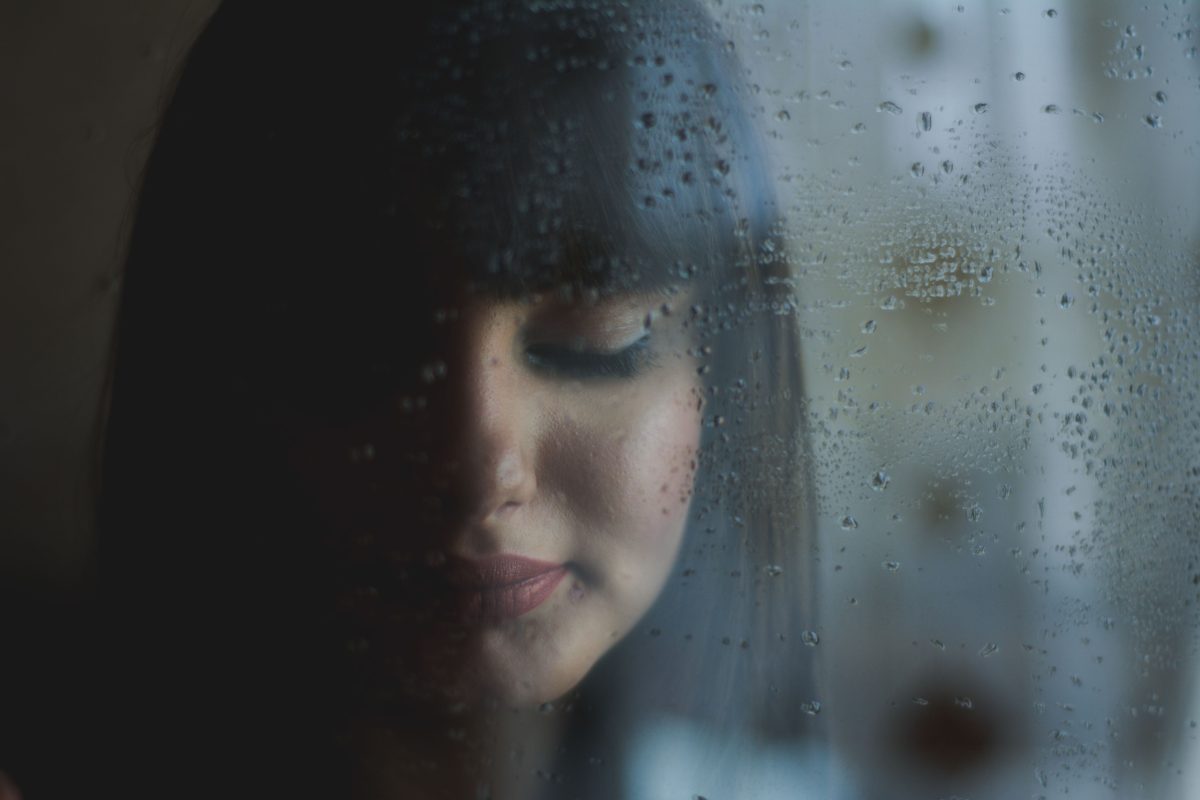 Mujer contemplando la lluvia desde la ventana